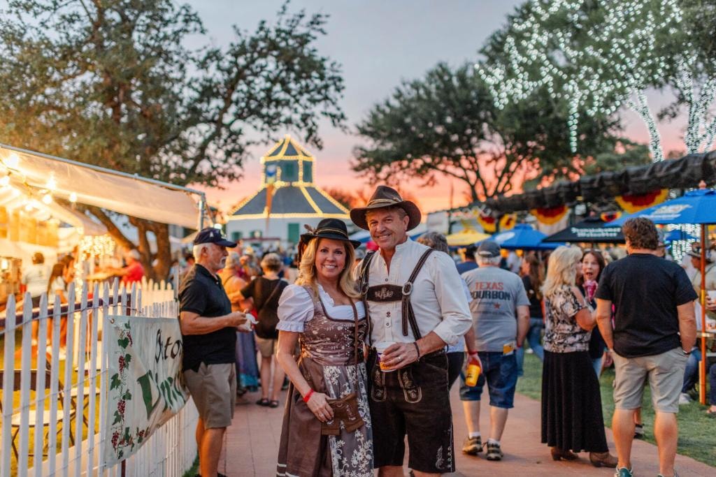 Fredericksburg Oktoberfest at Marktplatz in downtown Fredericksburg, Texas Hill Country — couple in traditional Bavarian attire celebrating at the annual German festival, 20 minutes from Willow Sky Ranch wedding venue