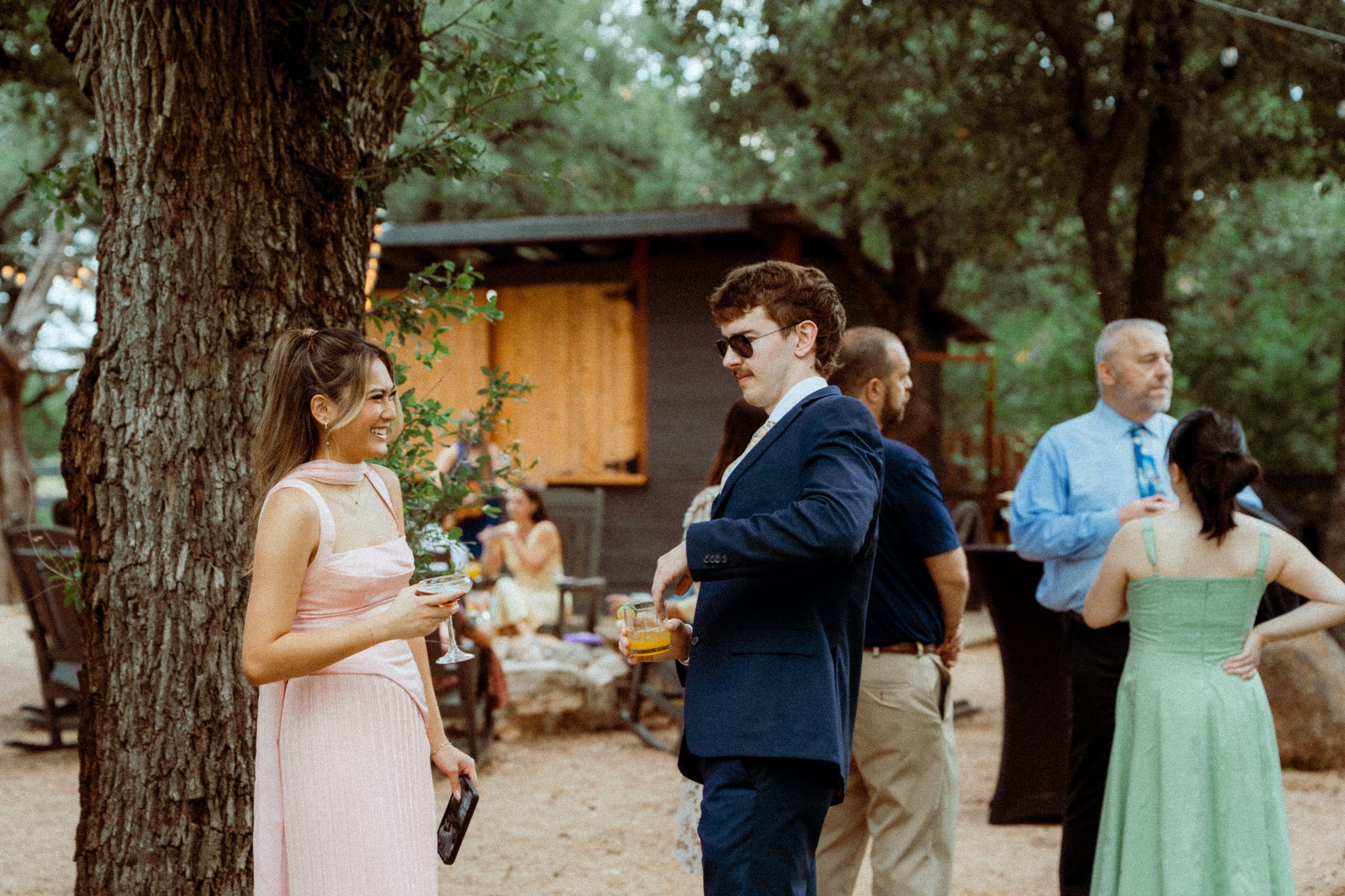 Cocktail hour at Willow Sky Ranch near Fredericksburg, TX — guests mingling under bistro string lights on the outdoor lawn at golden hour, Hill Country wedding venue near Austin and San Antonio, photographed by Zach Brigham Delude Photography